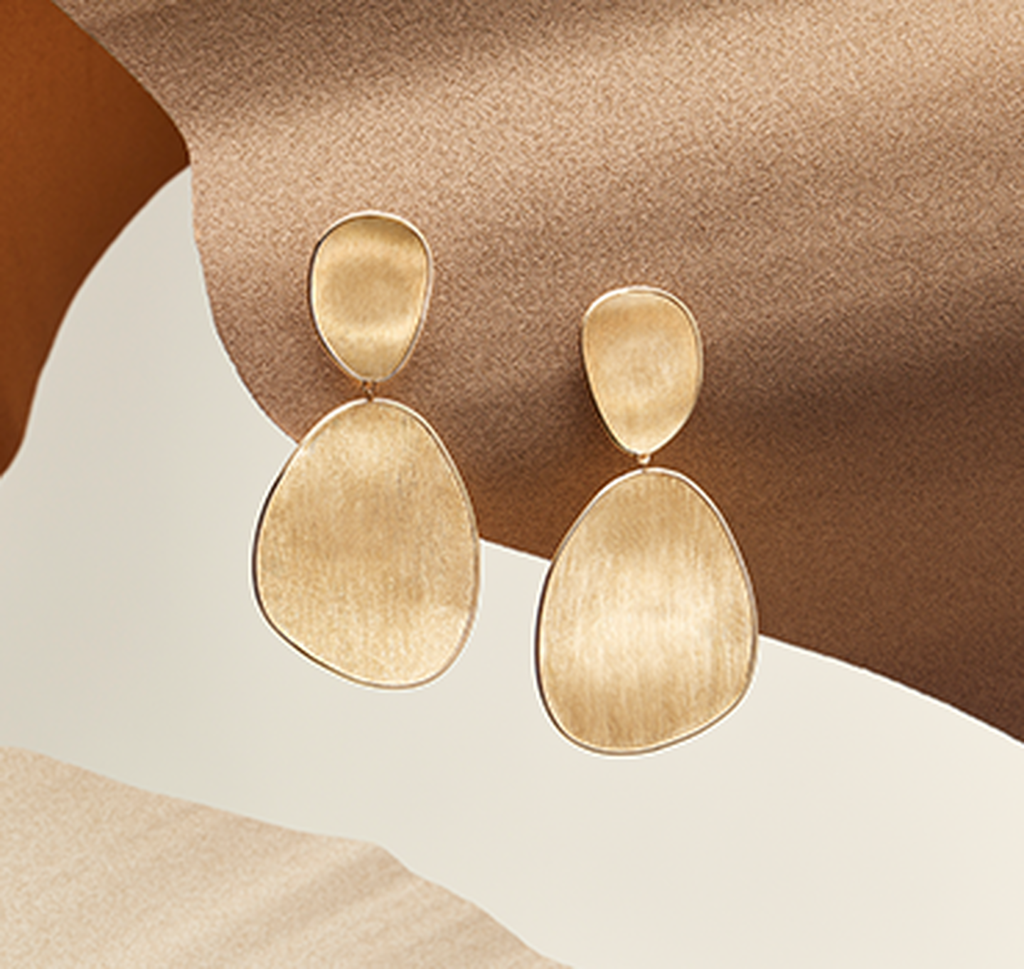 Lunaria earrings resting on a sandy background.